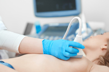 Professional gynecologist performing breast examination for her patient using ultrasound scanner...