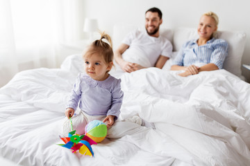 happy child with toys and parents in bed at home
