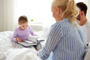 happy family reading book in bed at home