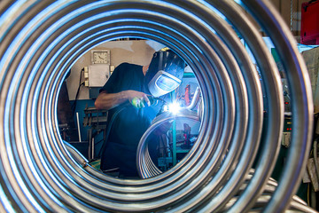 Worker is welding metal tubes.