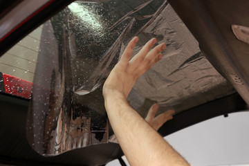 Worker applying tinting foil onto car window