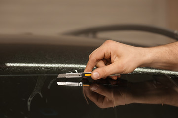 Worker applying tinting foil onto car window