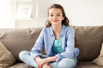 Obraz premium happy smiling preteen girl sitting on sofa at home
