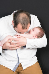 father with newborn baby in arms and kiss body