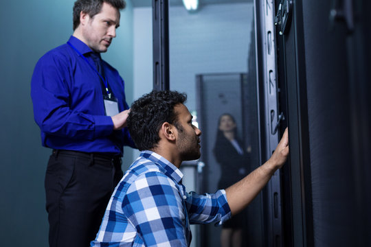 Serious nice man standing behind his colleague
