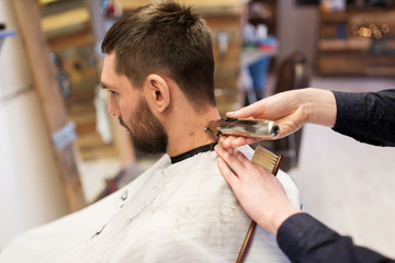 man and barber hands with trimmer cutting hair
