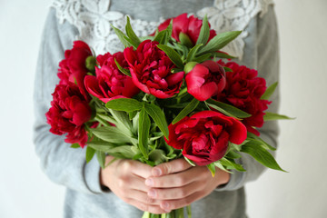 Young woman holding bunch of peonies on white background, closeup