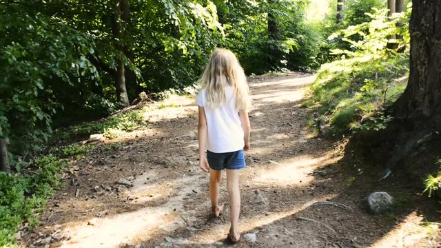 A girl walking barefoot on a forest path