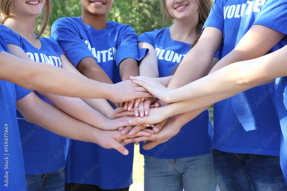 Poster Young people putting hands together outdoors. Volunteer concept