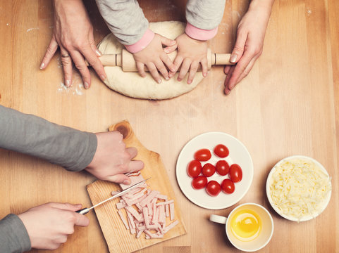 Hard-working hands. Cooking with children. Child and mother hands knead and roll dough with a rolling pin on the table. Toned. - Powered by Adobe