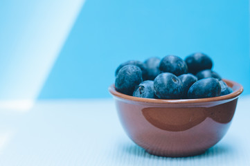 Fresh blueberries in a bowl on light blue background