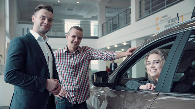 Sales Manager Gives the Client the Keys from the Car. Then smiling woman customer look straight at the camera
