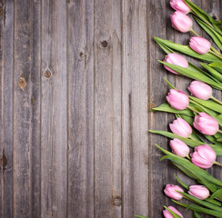 Row of tulips on wooden background with space for message. Mother's Day background. Top view.
