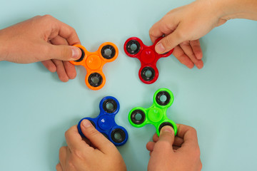 trendy fidget spinners - styled flat lay scene with hands holding colorful generic design spinners...