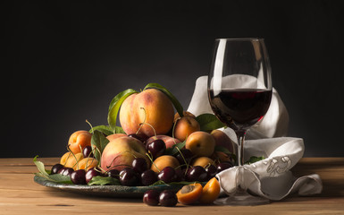 glass with red wine and tray with fruits