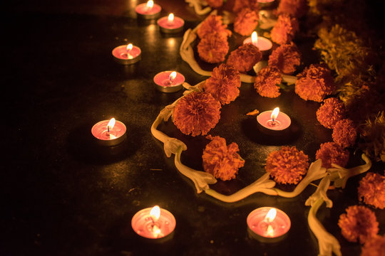 Side view of Rangoli flowers and candles or diyas placed beside them, Diwali lghts at night. Dark background Stock image.