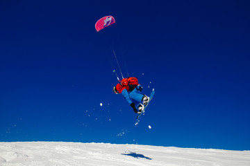 Snowboarder with a kite on fresh snow in the winter in the tundra of Russia against a clear blue sky. Teriberka, Kola Peninsula, Russia. Concept of winter sports snowkite.