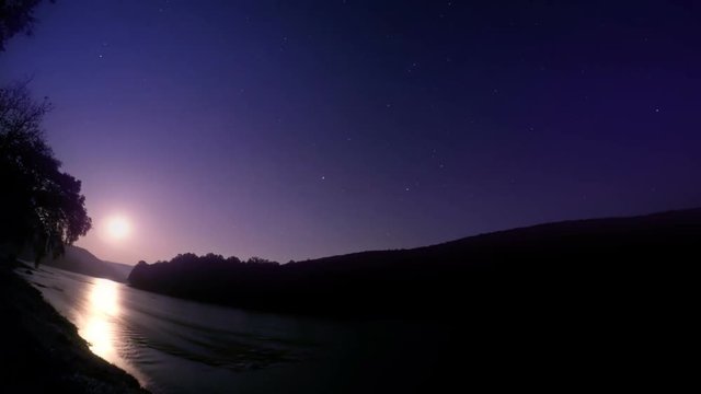 Night time lapse of moon rising over a river