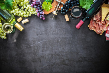 Obraz na płótnie Canvas Wine bottles with grapes, cheese, ham and corks