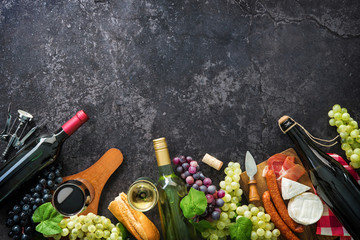 Wine bottles with grapes, cheese, ham and corks