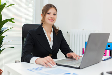 Portrait of a young smiling businesswoman using her computer