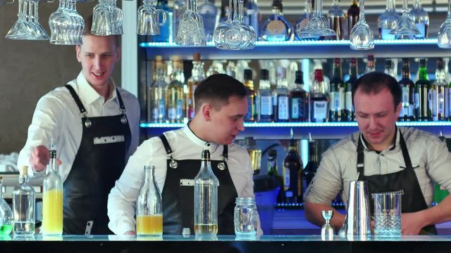Three bartenders serving cocktails and working in a classy bar