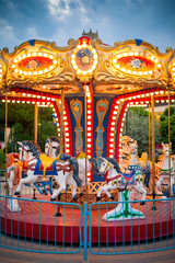Carousel with lights in evening under stormy clouds