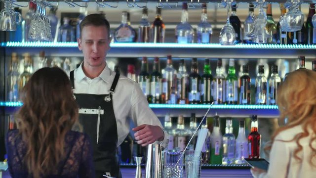Handsome bartender serving cocktail to beautiful woman in a classy bar