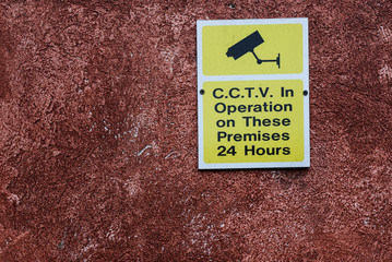 Area under cctv surveillance warning sign on wall