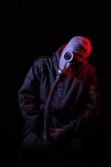 Hombre joven con máscara de gas subiéndoselos la bragueta
