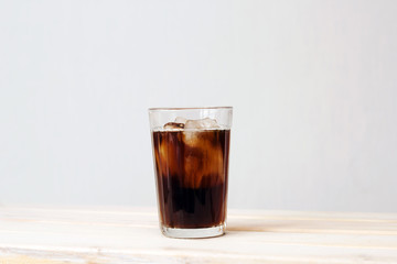 black iced coffee against white wall