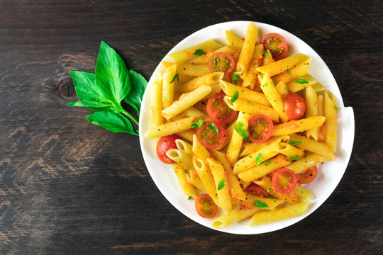 Penne pasta with tomato sauce and fresh basil leaves