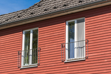 Fenster in einer roten Fassade aus Holz