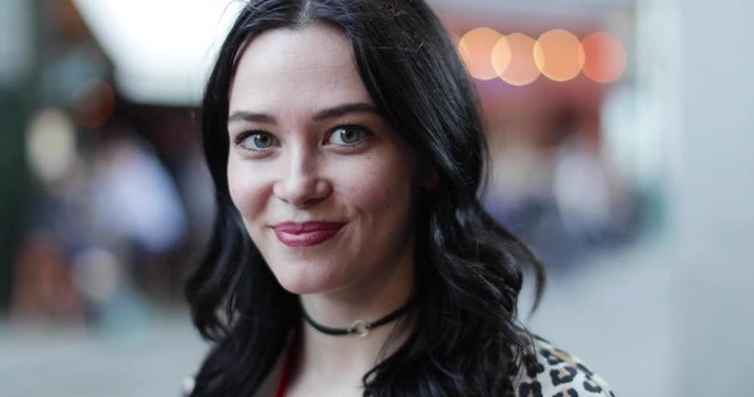 Portrait of young adult female turning to look at camera on street