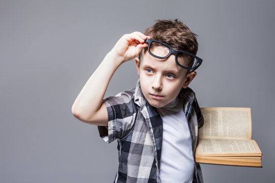 Smart pupil in glasses with textbook in hands
