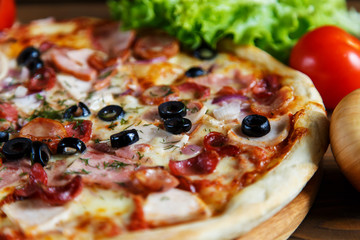 Delicious homemade pizza with mozzarella, ham, olives and fennel.