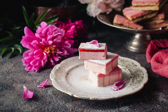 Fruit cakes taffy (lucum) and sand cakes on a dark background, decorated with peonies. Summer light and delicious dessert. Close up