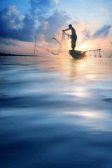 Fishermen on boat fishing with a fishnet,the old traditional equipment of Thai fishery.Silhouette...