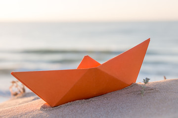 Orange paper boat on a beach