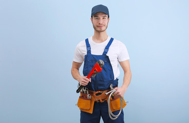 Naklejka premium Handsome young plumber in uniform on color background