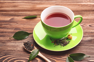 Cup of tea and spoon of brew on wooden background