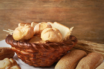 Baked basket with fresh bread on wooden background