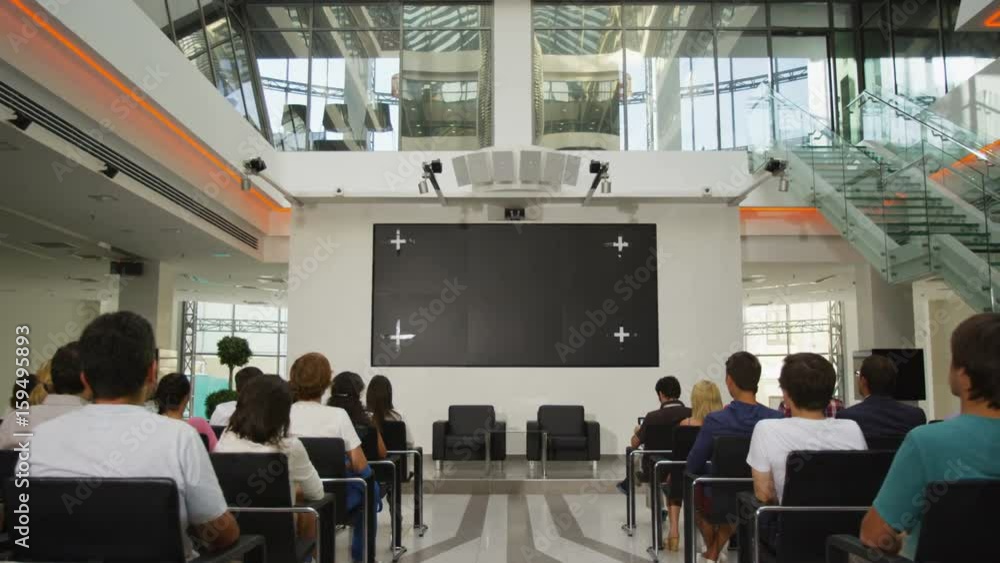 Wall mural camera moves along pass between waiting for lecture listeners