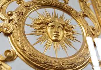 Detail view of golden ornate of Chateau de Versailles depicting human face.