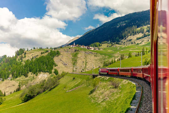 Red train slowly climbing to the Bernina Pass in the Swiss Alps - 1