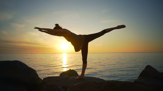 Healthy young beautiful girl practice yoga asanas sea coast sunrise slow motion