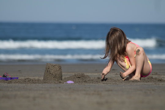A young girl is building with sand at the beach (Series 1)
