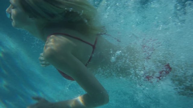 Medium slow motion tracking shot of woman diving into pool. Cedar Hills, Utah, United States
