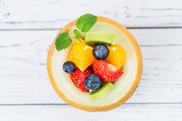 Fruit salad in melon on wooden table. Top view