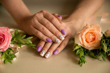 Obraz na płótnie Canvas Natural nails with beautiful manicure, purple polish with blossom flowers on women nails near bouquet of fresh flowers